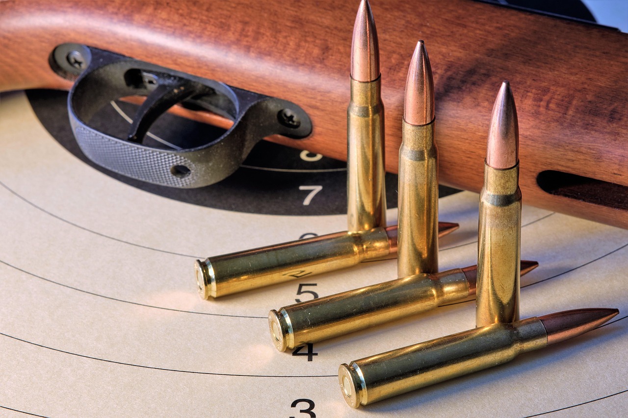 Rifle cartridges standing on a paper target beside a hunting rifle
