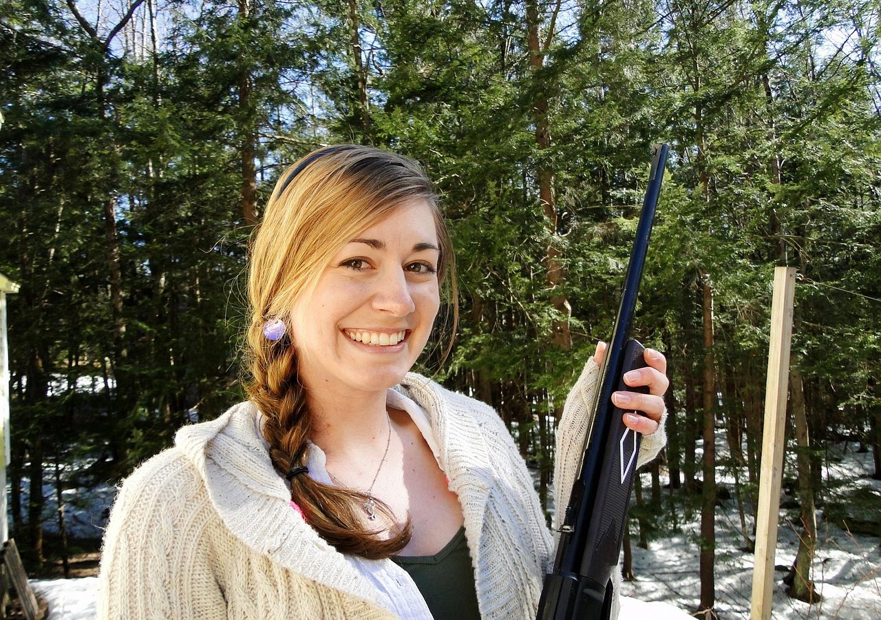 Hunter holding a rifle safely with the muzzle pointed up in winter woods